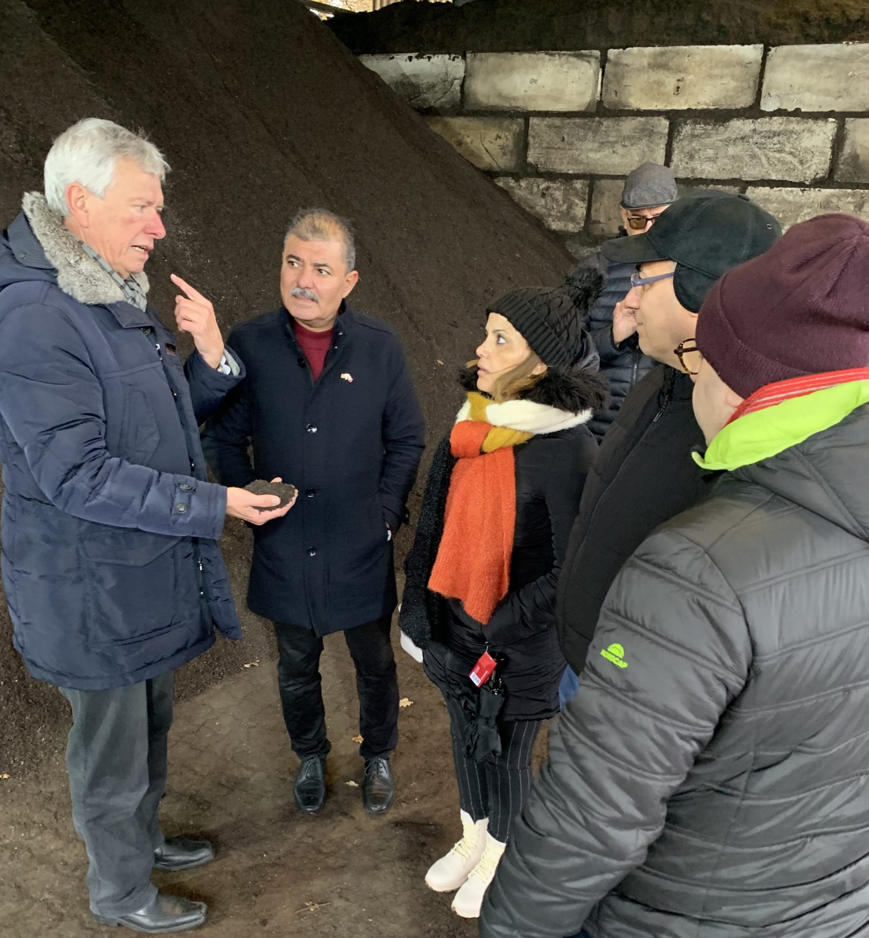 awm-Betriebsleiter Patrick Hasenkamp und vier Gäste aus Monastir vor einem aufgeschütteten Berg Kompost