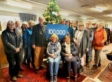 Eine Gruppe ehrenamtlicher Helfer des Edelfundus mit einem Schild, auf dem die Spendensumme 100.000 Euro zu lesen ist.